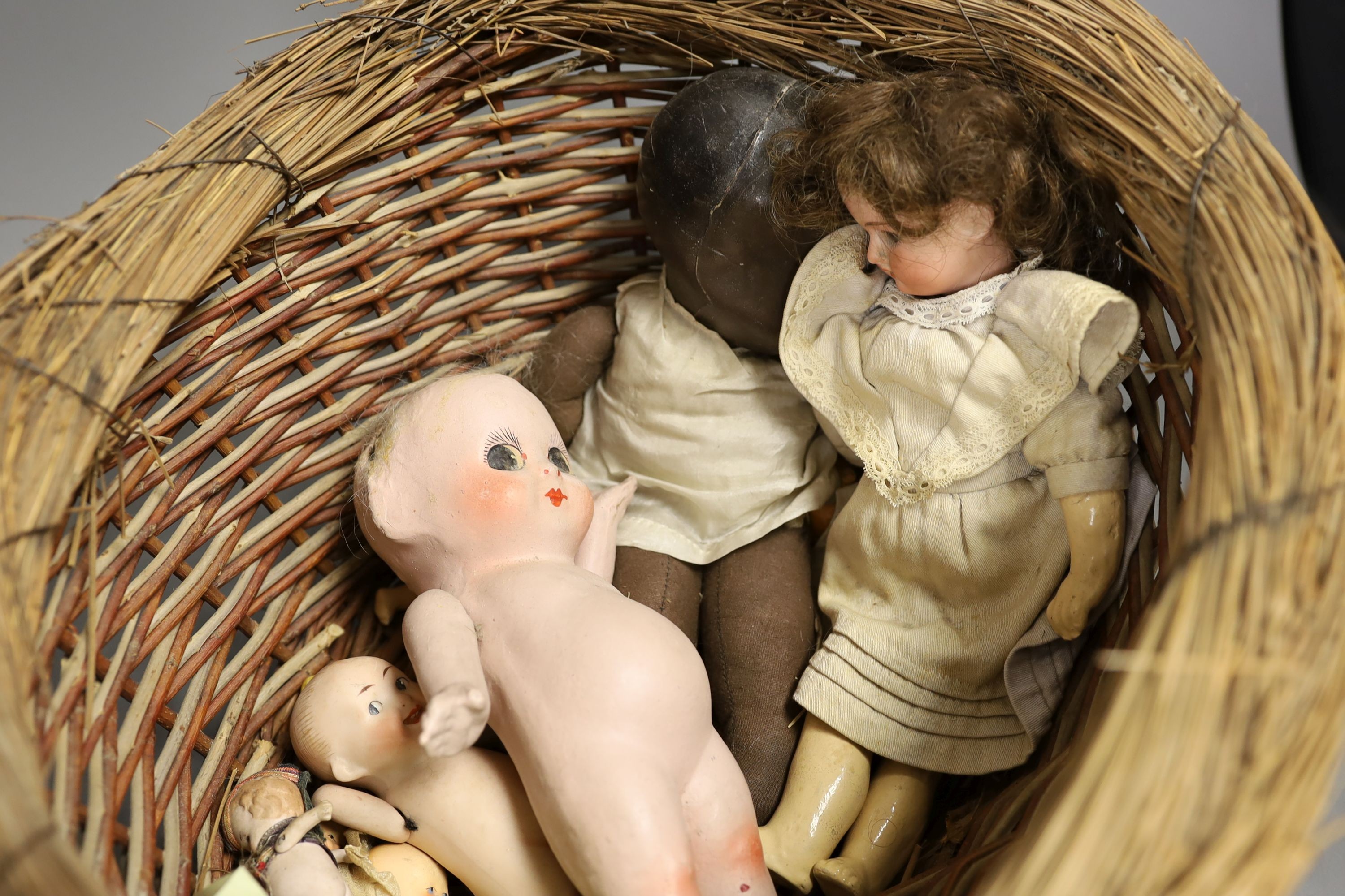 An early 20th century Max Handwerke bisque doll with open mouth and sleeping eyes, H 46 cms, one other smaller German bisque doll, a composition Chinese baby doll and nine others, some miniature and incomplete.